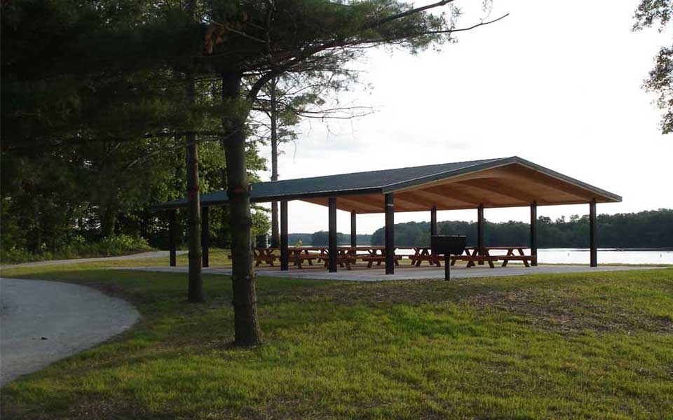 shelter with picnic tables and water behind 